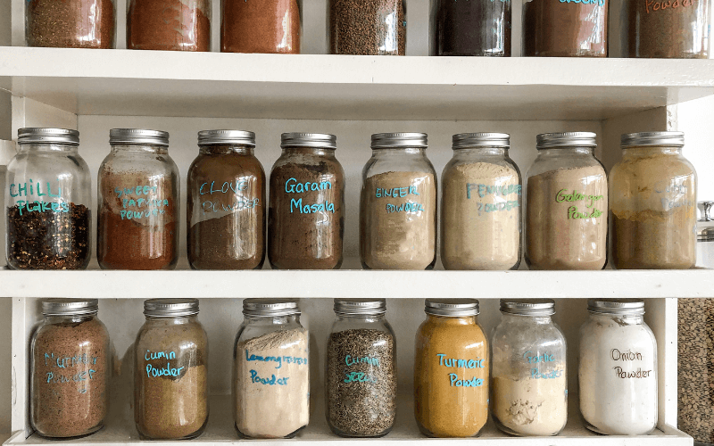 Indian kitchen shelf with labeled glass jars for dals and grains